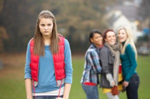 Upset Teenage Girl With Friends Gossiping In Background